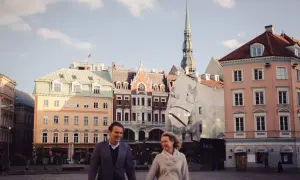 Para spaceruje po Rynku w Rydze, w tle zabytkowe kamienice i wieża kościelna.