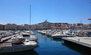 Widok na port w Marsylii z wieloma łodziami i budynkami w tle.