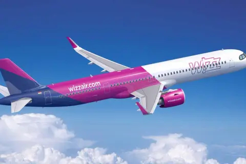 Samolot Wizz Air w locie na tle błękitnego nieba z chmurami.