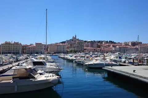 Widok na port w Marsylii z wieloma łodziami i budynkami w tle.
