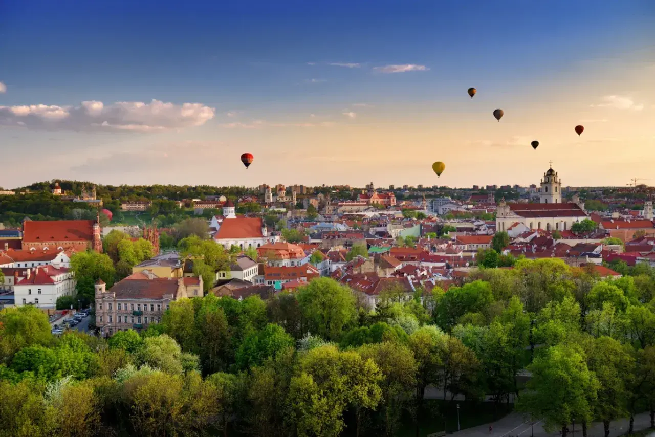 Widok na Wilno z lotu ptaka, z kilkoma balonami na gorące powietrze na niebie.