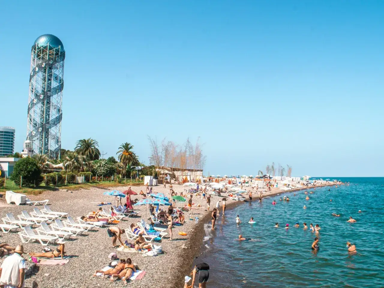 Tłum ludzi na plaży w Batumi, z charakterystyczną wieżą w tle. Odpowiedź na pytanie: czy w Gruzji jest bezpiecznie? Tak, wygląda na to, że można tu spokojnie wypoczywać.