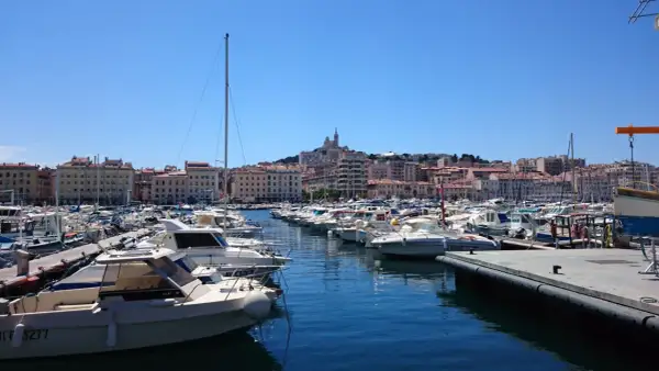 Widok na port w Marsylii z wieloma łodziami i budynkami w tle.